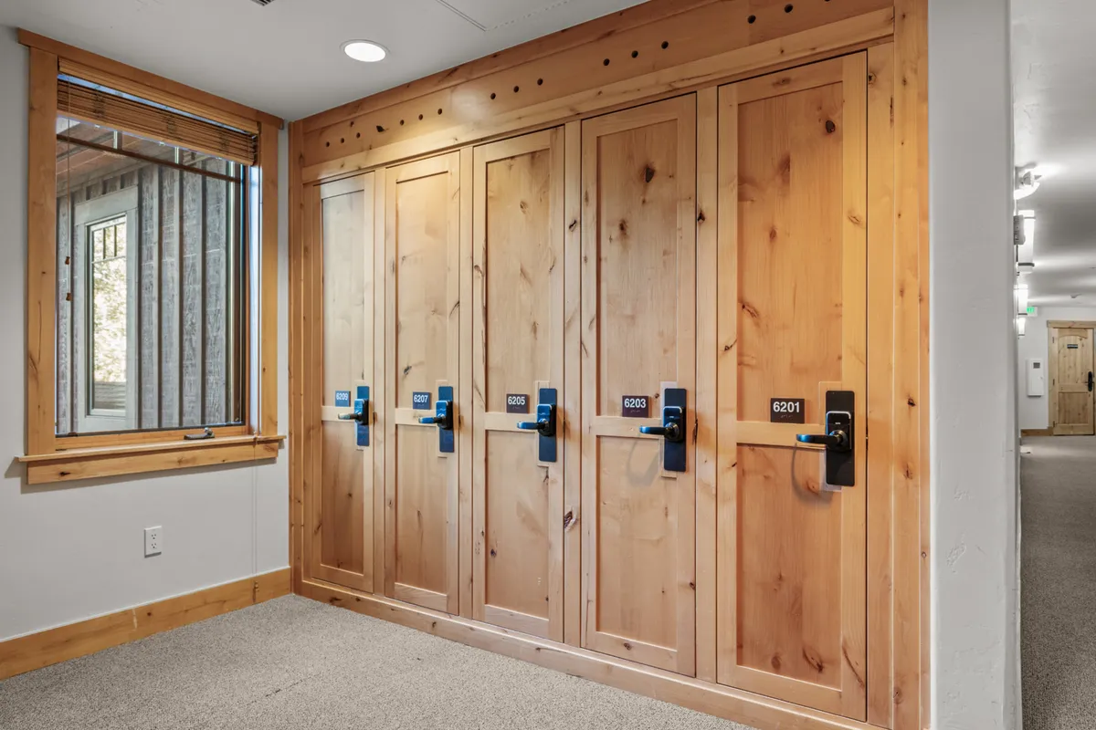 A mudroom or storage area featuring wooden lockers with natural light filtering through a window, creating an organized and welcoming entry space. The lockers are ideal for stashing outdoor gear like skis, bikes, or hiking boots after a day of adventure.