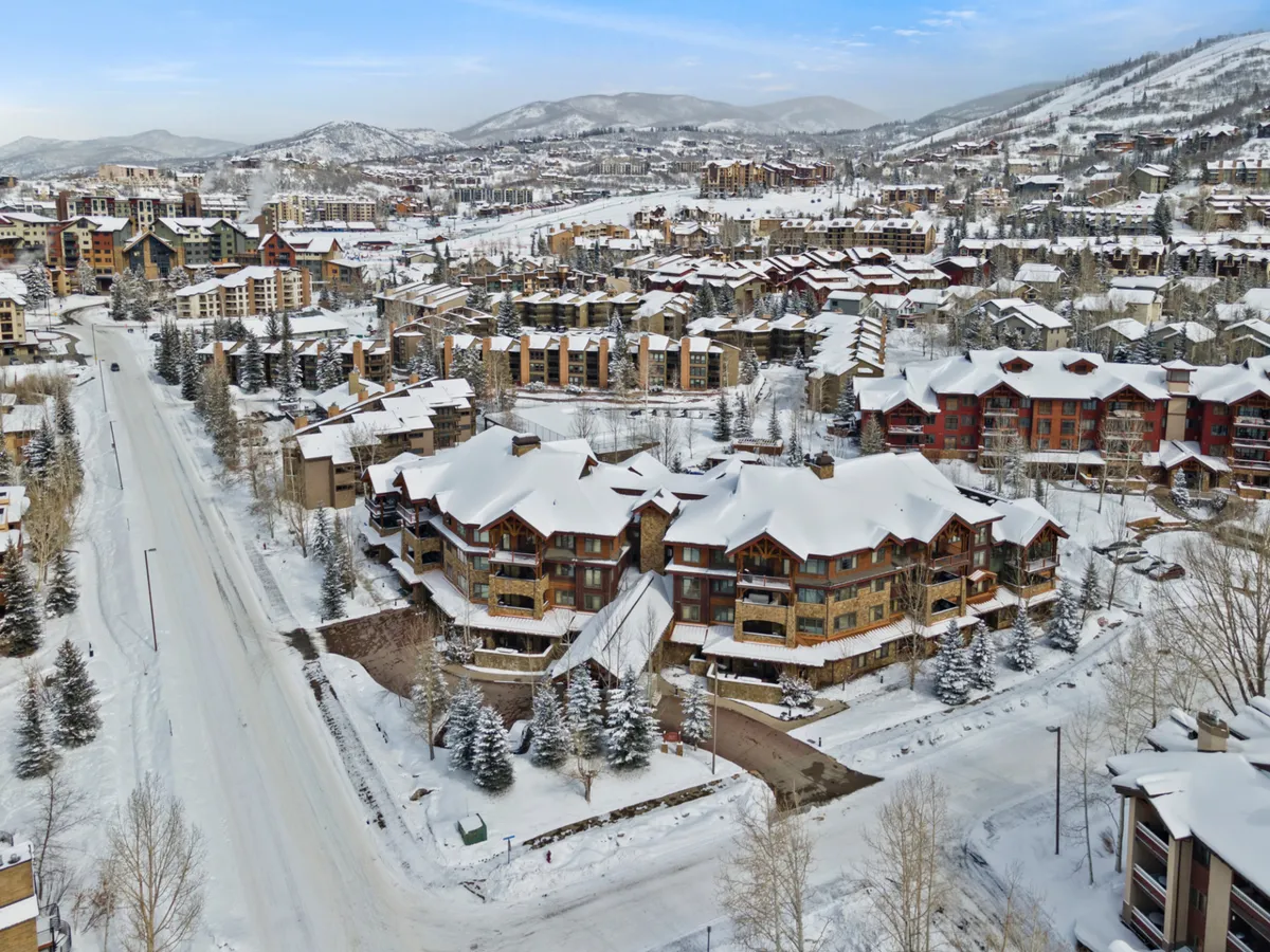 A picturesque winter scene of Steamboat’s mountain village, featuring snow-covered rooftops, rustic wooden architecture, and majestic surrounding mountains. The quiet road and soft winter light evoke the coziness and charm of the area, inviting exploration of local shops, dining, and nightlife.